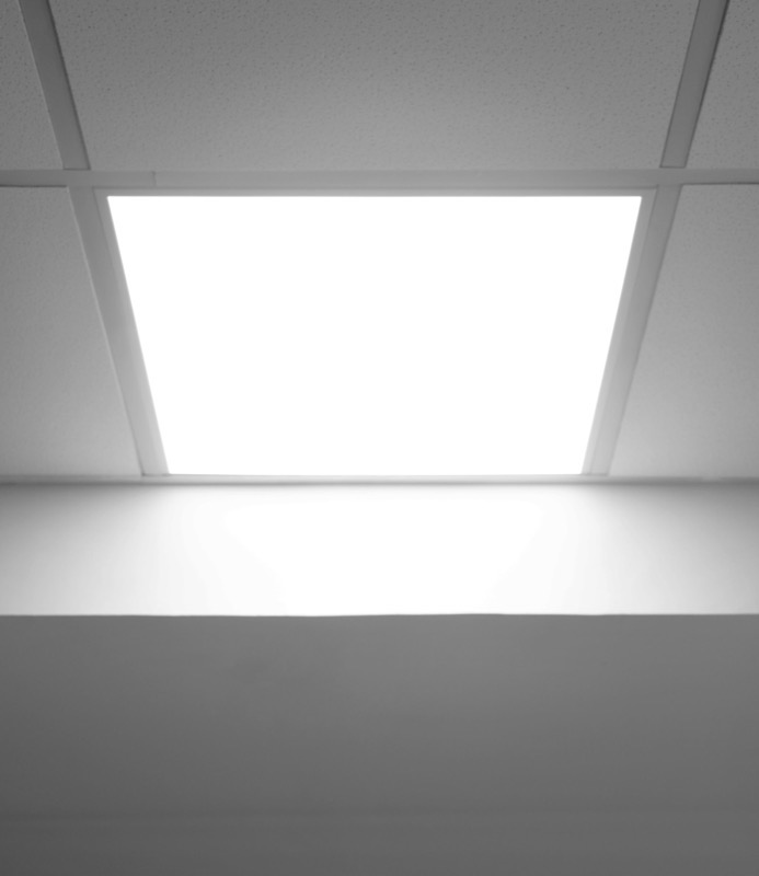 A recessed LED panel set into a standard suspended office ceiling grid